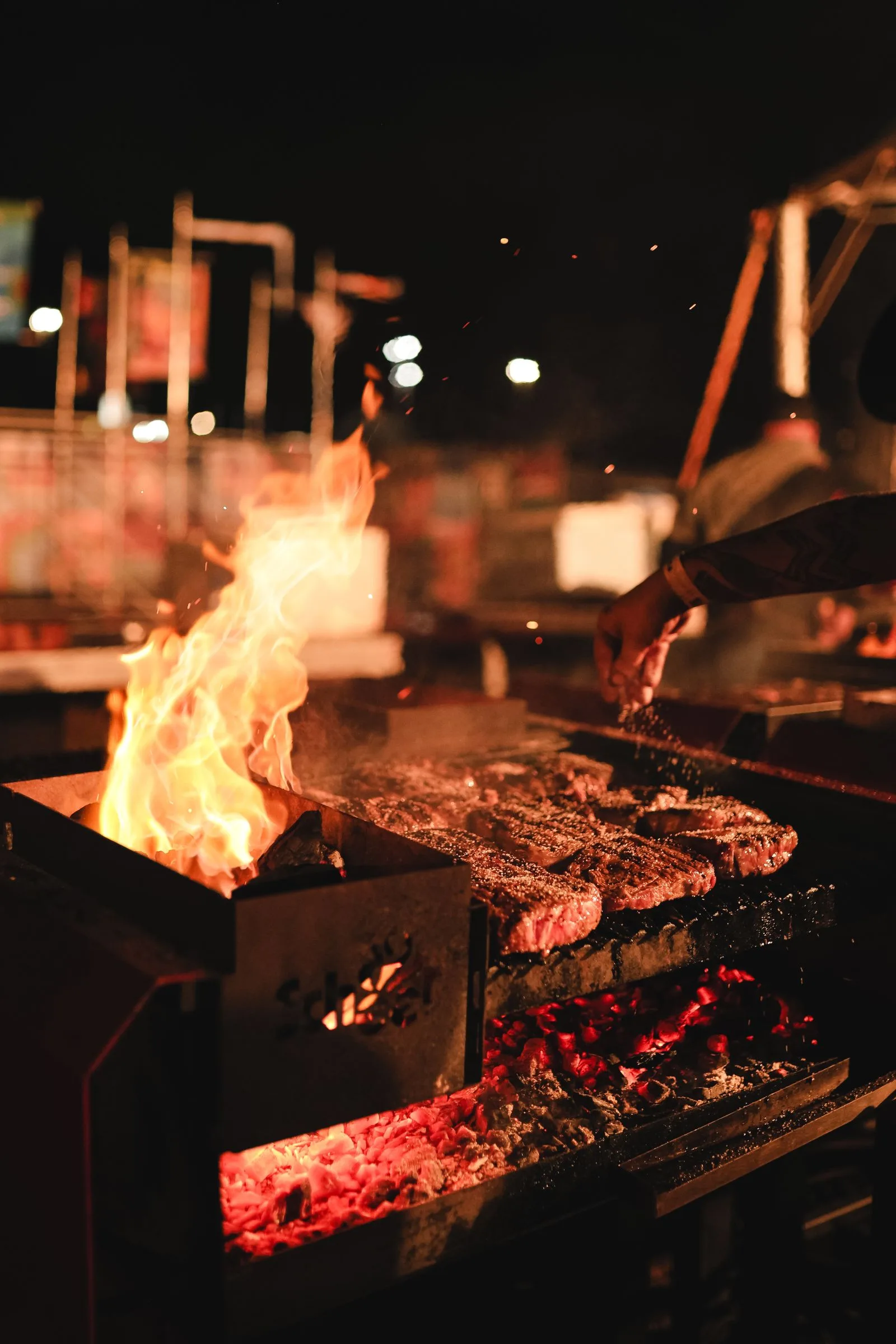 Steaks searing over live fire on a grill at night